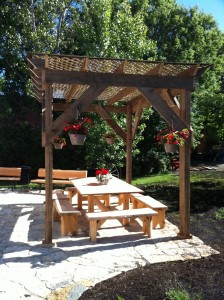 Large backyard with pergola, patio set, benches, fire pit at the Prospector's House in Haileybury / Cours arrière de la Maison des prospecteurs avec pergola, ensemble de patio, et feu de camp.