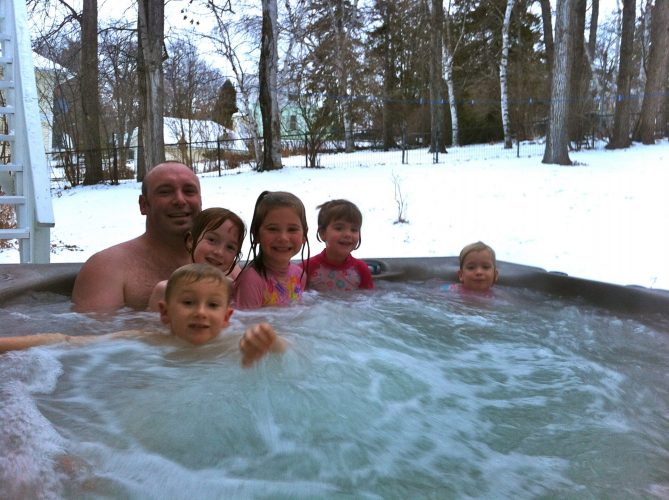 A young family enjoying the spa at the Presidents' Suites. The spas are operational year around. / une jeune famille profitant du spa extérieur en hiver aux Suites des Présidents.